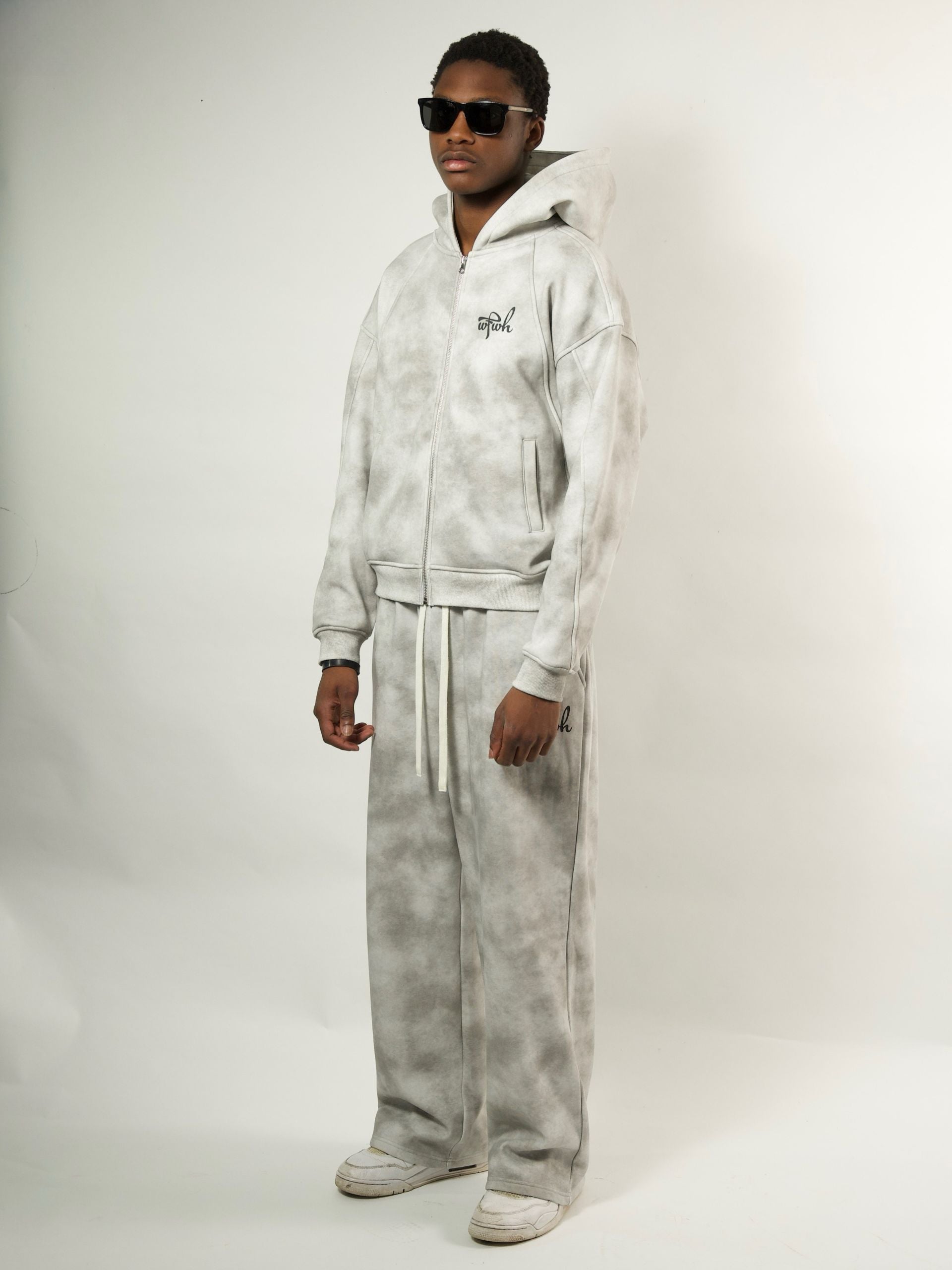model wearing a dust wfwh tie-dye tracksuit with sunglasses on a white background