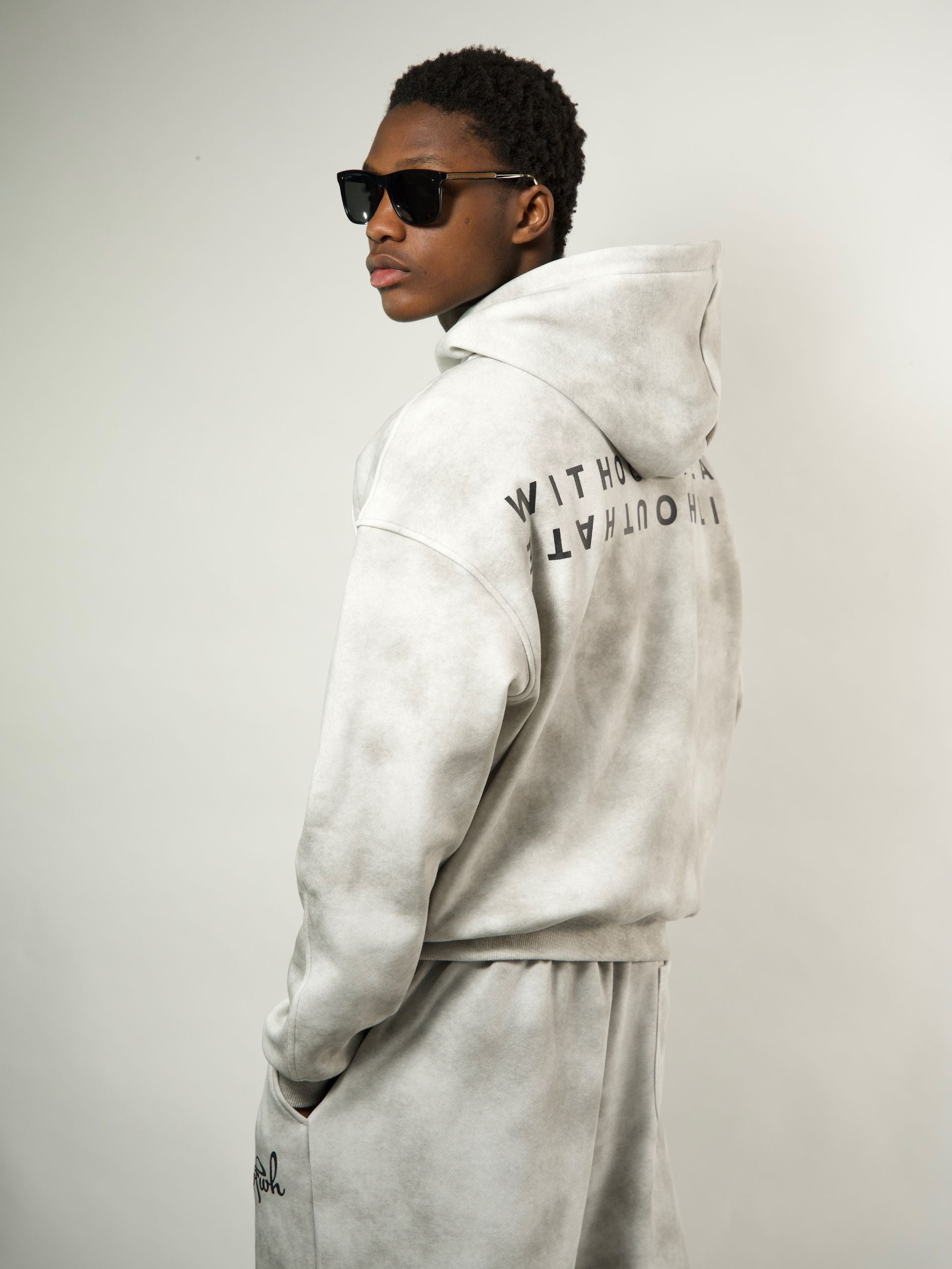 Person wearing a gray zipper with text on the back against a plain background